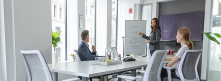 office meeting with woman pointing at whiteboard